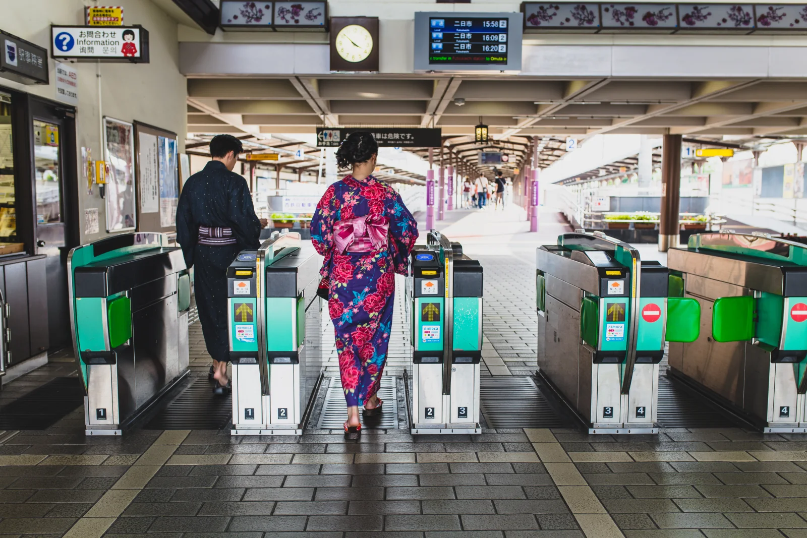 Japonya'da bir tren istasyonunda otomatik turnikelerden geçen kimonolu çift