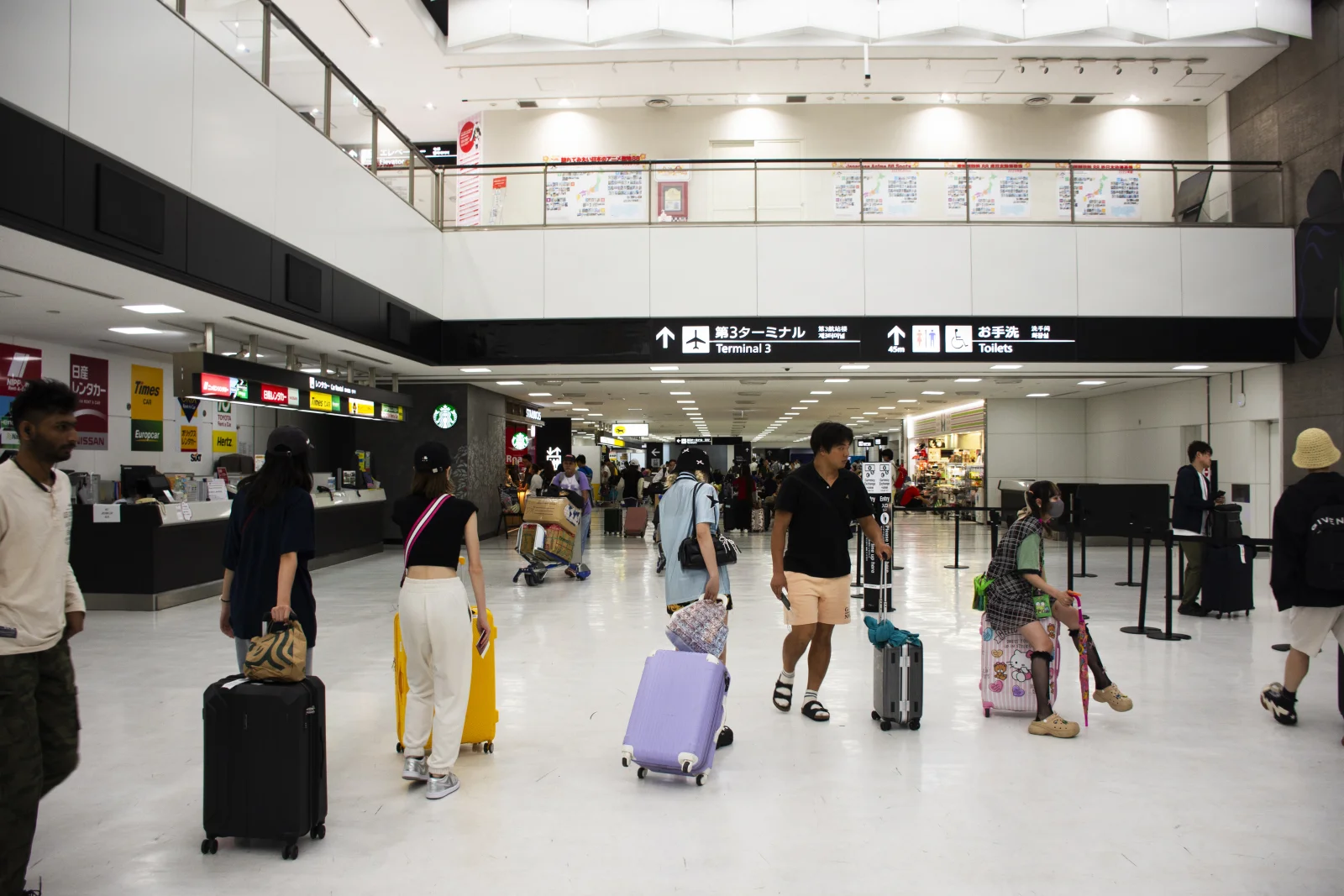 Narita Uluslararası Havalimanı terminalinde bavullarıyla yürüyen yolcular