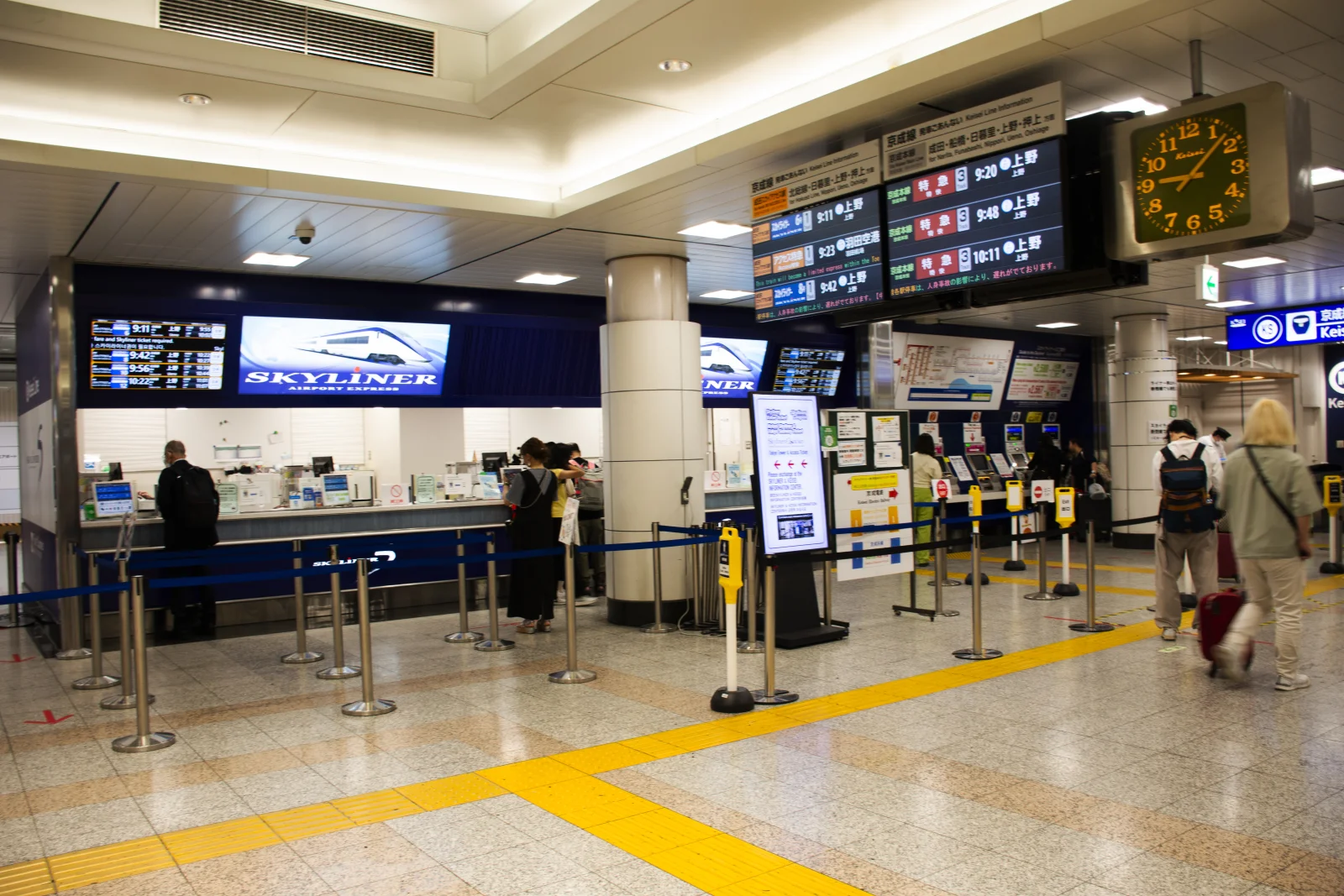 Narita Havalimanı istasyonunda Keisei Skyliner bilet gişesi önünde bekleyen yolcular